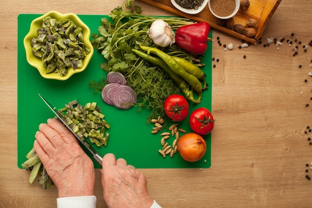 Ingrediënten voor het koken van gezonde vegetarische maaltijden vol vitamines vrouw die sperziebonen snijdt