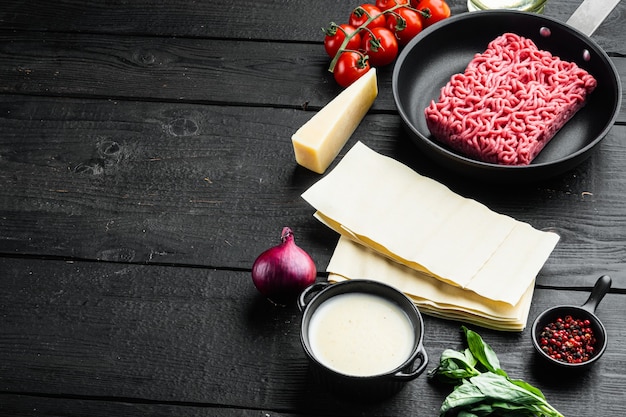 Ingrediënten voor het koken van Italiaanse lasagne set, op zwarte houten tafel achtergrond, met kopie ruimte voor tekst