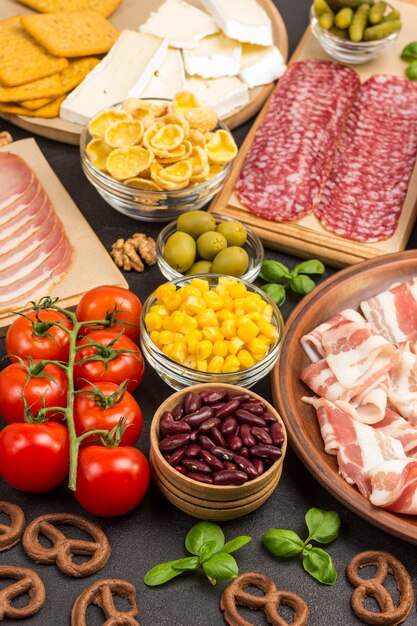 Ingrediënten voor het koken van ontbijt: spek, maïs, tomaten, basilicum.