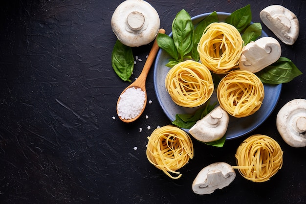 Ingrediënten voor het koken van traditionele pasta met champignons in plaat op donkere stenen oppervlak Copyspace