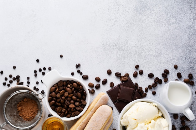 Ingrediënten voor het maken van Italiaanse desserttiramisu, savoiardi, mascarpone, cacaopoeder en chocolade op licht beton