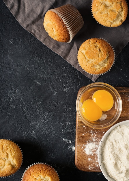 Ingrediënten voor het maken van muffins op zwarte textuur, kopie ruimte, bovenaanzicht, verticaal