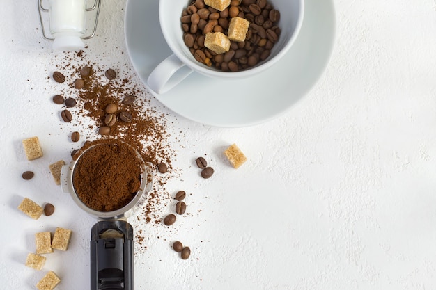 Ingrediënten voor koffie: gemalen koffie in de hoorn van de koffiemachine, suiker en een kopje. Bovenaanzicht met kopieerruimte