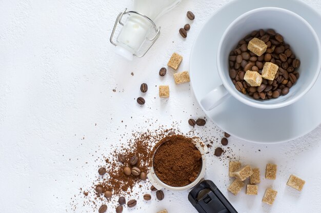 Ingrediënten voor koffie: gemalen koffie in de hoorn van de koffiemachine, suiker en een kopje. bovenaanzicht met kopieerruimte