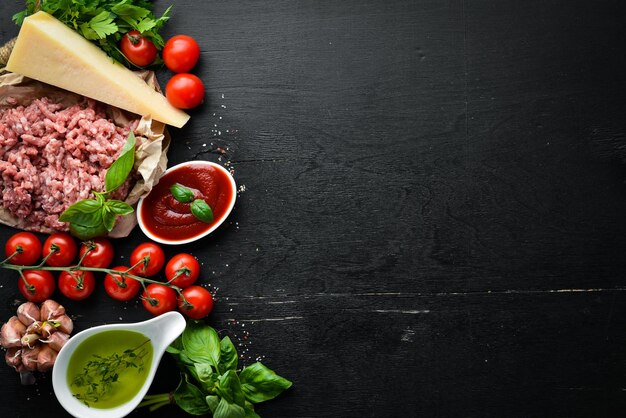 Ingrediënten voor kooksaus Bolognese Op een zwarte achtergrond Bovenaanzicht Vrije ruimte voor uw tekst
