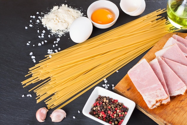 Ingrediënten voor Pasta Carbonara op zwarte leisteen achtergrond