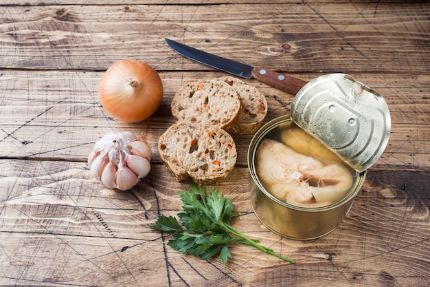 Ingrediënten voor soepkruik met roze zalmvissen, stukken brood, ui en knoflook met greens op houten achtergrond.