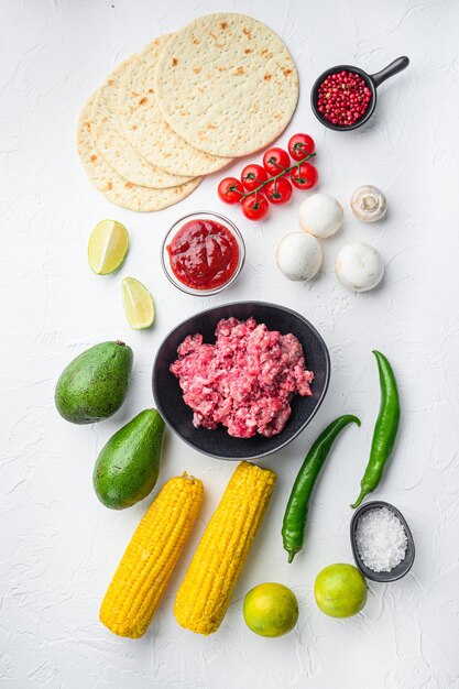 Ingrediënten voor taco's met rundergehakt, maïstortilla's, chili, avocado, op witte achtergrond. Bovenaanzicht.