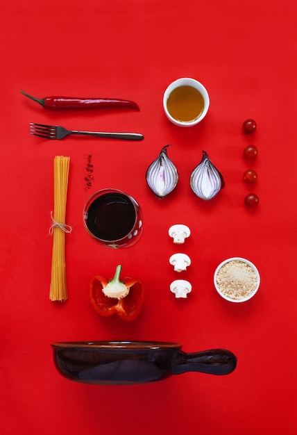 Ingrediënten voor traditionele Italiaanse pasta koken met keramische pan Bovenaanzicht close-up op rode achtergrond