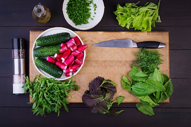 Ingrediënten voor verse salade van komkommers, radijs en kruiden. Plat leggen. Bovenaanzicht