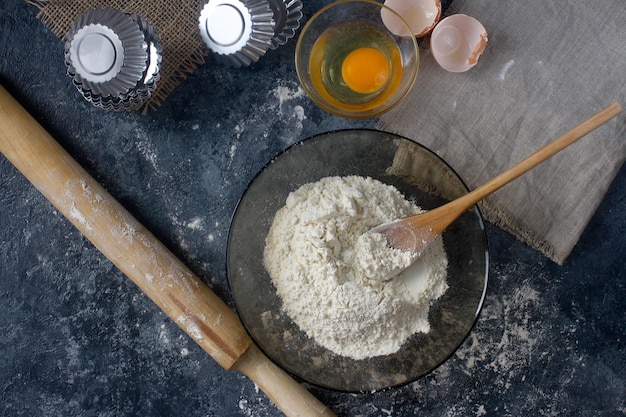 Ingrediënten voor zelfgemaakte koekjes in rustieke keukenmeel eieren boter op donkere stenen tafel