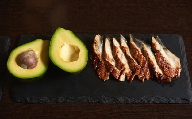 Ingredients avocado and eel on the black stone plate