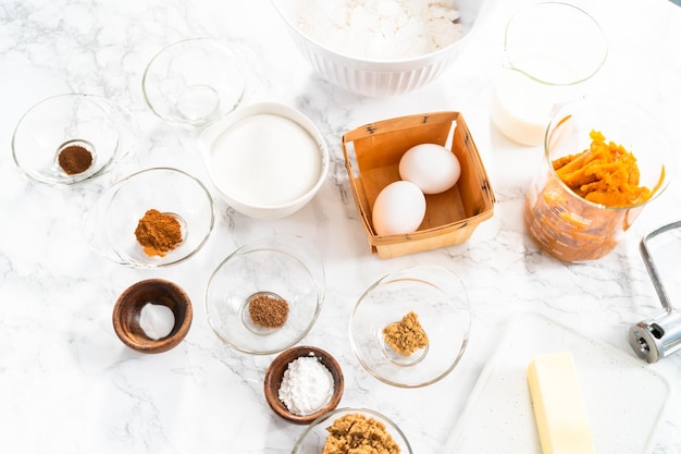 Ingredients to bake pumpkin spice cupcake on a marble countertop.