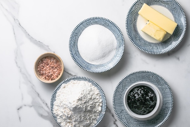 Ингредиенты для выпечки булочек пшеничная мука йогурт растительное масло соль разрыхлитель на мраморном фоне вид сверху Приготовление вкусной домашней еды