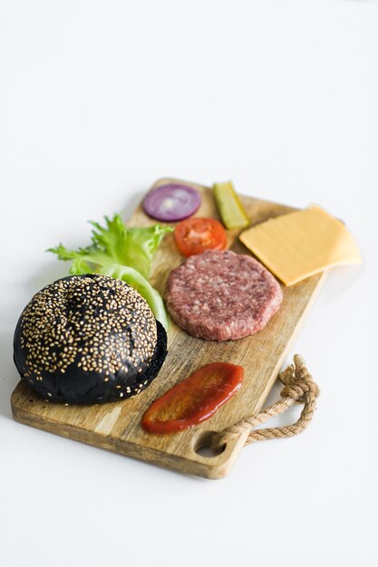 Photo ingredients for the black burger on wooden cutting board.