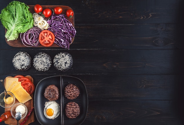 Ingredients for a black burger on a wooden surface