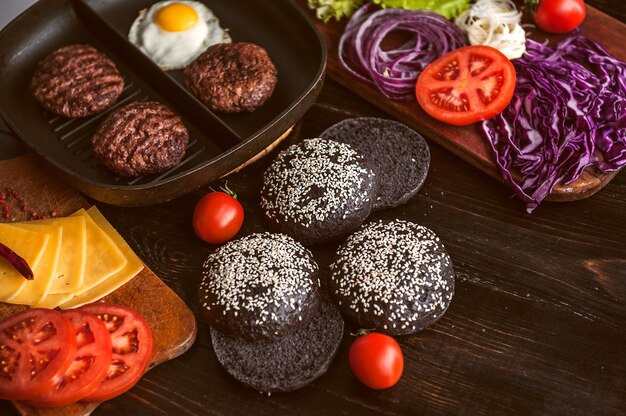 Ingredients for a black burger on a wooden surface