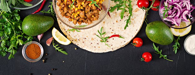 Ingredients for burritos wraps with beef and vegetables on black. Mexican food. Top view. Flat lay