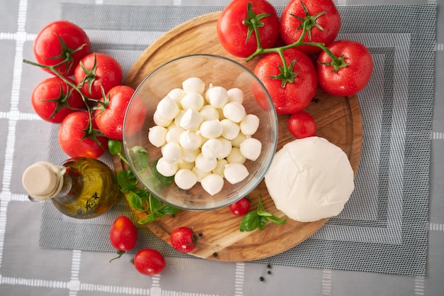 Photo ingredients for caprese salad mini mozzarella cheese in glass bowl tomato and basil