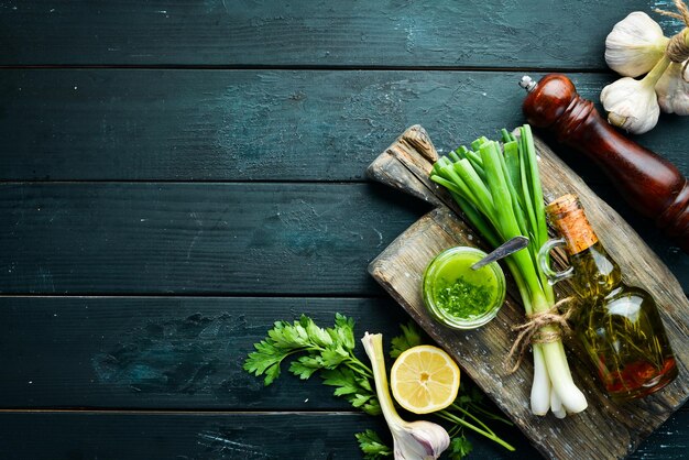 Ingredients for chimichurri sauce fresh parsley onion garlic olive oil lemon On a black background Top view free space for your text