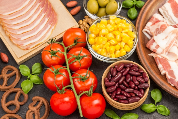 Ingredients for cooking breakfast: bacon corn tomatoes basil.