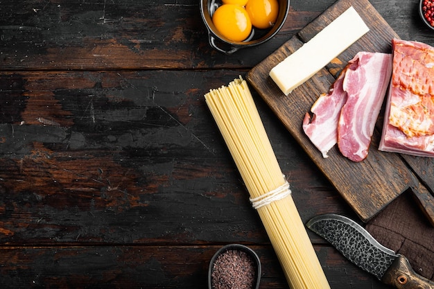 Ingredients for cooking Carbonara pasta spaghetti with pancetta egg and hard parmesan cheese on old dark wooden table top view flat lay with copy space for text