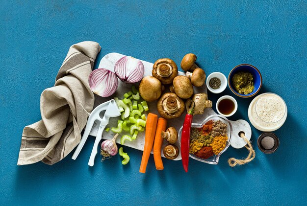 Ingredients for cooking Indian curry from vegetables pumpkins and mushrooms on a blue background and spices shot from above copy space