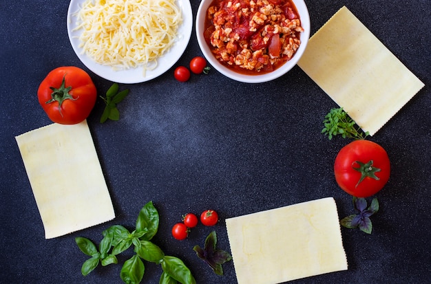 Ingredients for cooking lasagna. Recipe for homemade Italian lasagna with tomato sauce and meat. Tomatoes, basil, meat sauce, mozzarella cheese, lasagna noodles. Italian food. Top view. Copy space