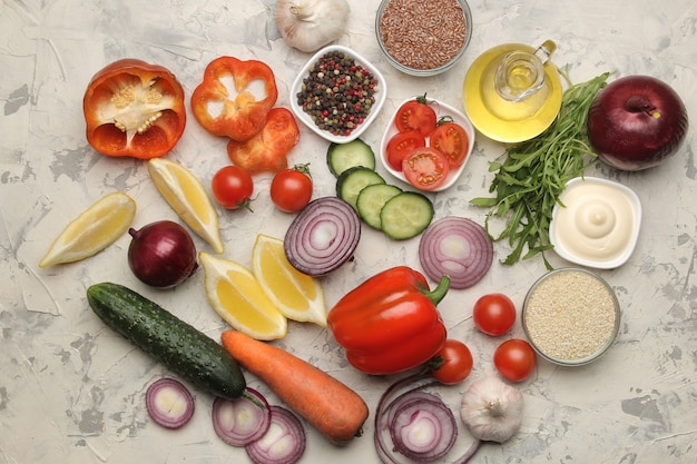 Ingredients for cooking salad. Various vegetables and spices carrots, tomatoes, onions, cucumbers, peppers and arugula on a light background. top view.