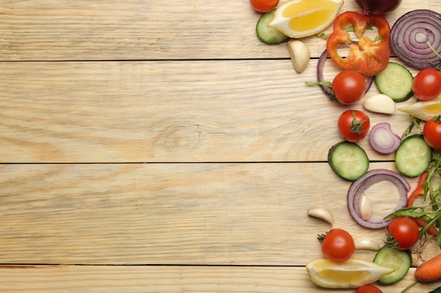 Ingredients for cooking salad. Various vegetables and spices carrots, tomatoes, onions, cucumbers, peppers and arugula on a natural wooden table. top view.