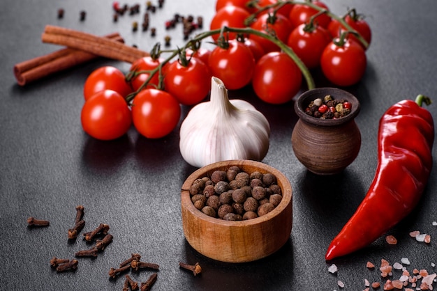 Photo ingredients for cooking, spices, garlic, tomatoes and herbs on a black background