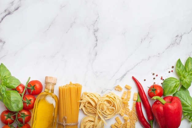 ingredients for cooking on a white marble table Tomatoes pasta basil and oil on a white