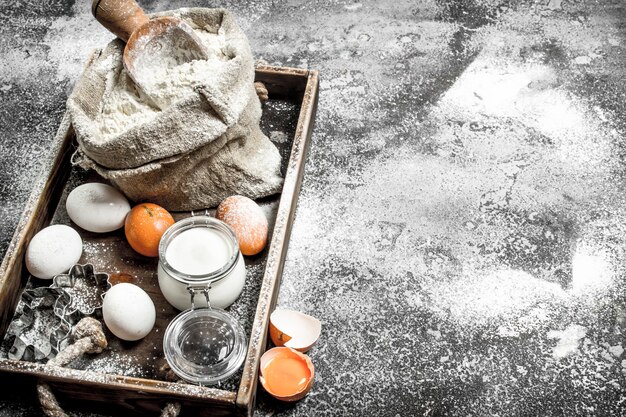 Ingredients for dough in a wooden tray on rustic table.