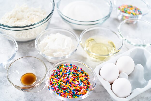 Ingredients in glass mixing bowls to bake funfettti bundt cake.