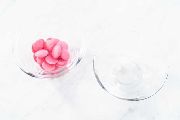 Ingredients in glass mixing bowls to make mini pink chocolates.