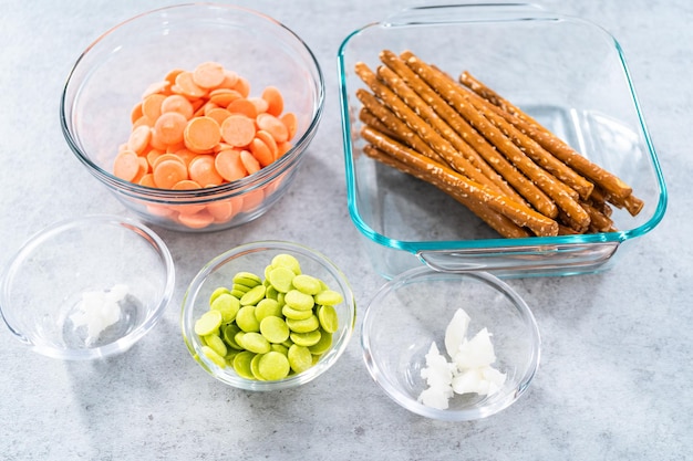 Ingredients in glass mixing bowls to prepare carrot chocolate covered pretzels.