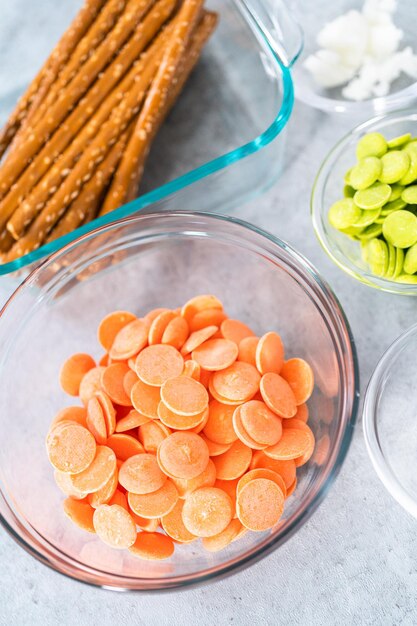 Ingredients in glass mixing bowls to prepare carrot chocolate covered pretzels