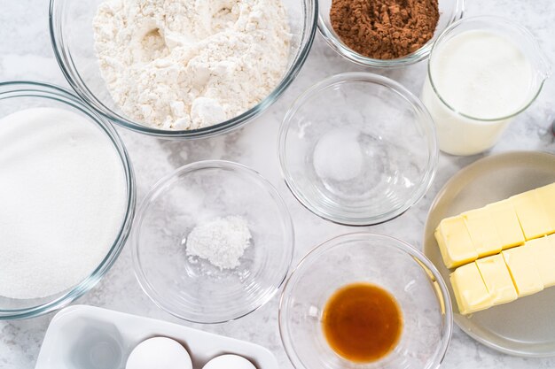 Ingredients in glass mixing bowls to prepare red velvet bundt cake.