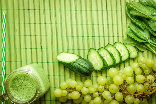 Ingredients for Green detox smoothie. Spinach, grape, cucumber on green background. Flat lay with place for text. Vegan and healthy food concept