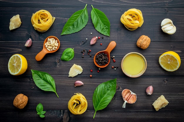 The ingredients for green pesto sauce on dark wooden background.