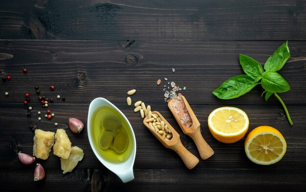 The ingredients for green pesto sauce on dark wooden background.