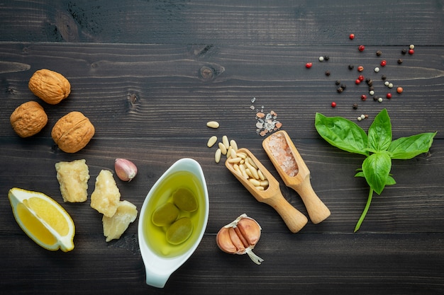 The ingredients for green pesto sauce on dark wooden background.