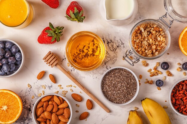 Ingredients for a healthy breakfast - granola, honey, nuts, berries and fruits