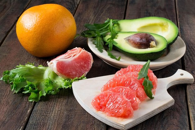 Photo ingredients for a healthy salad: avocado, grapefruit, arugula and lettuce on a wooden background. selective focus