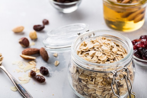 Ingredients for homemade oatmeal granola in glass jar. 