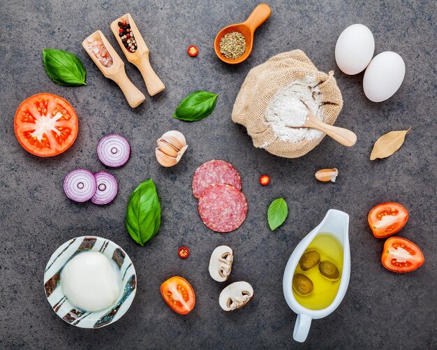 Photo the ingredients for homemade pizza on dark sthe ingredients for homemade pizza on dark stone backgroundtone background