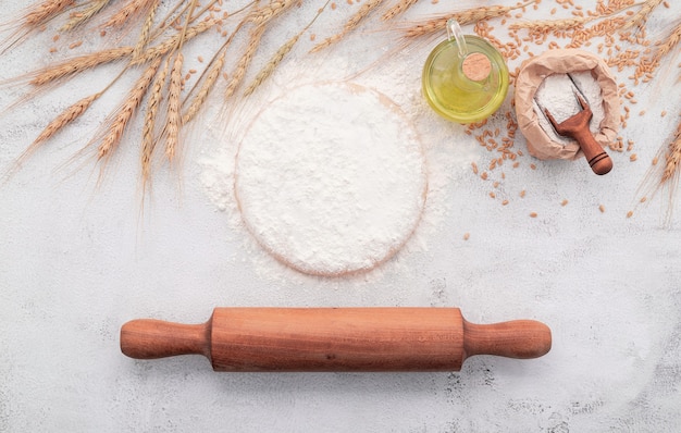 The ingredients for homemade pizza dough with wheat ears ,wheat flour and wheat grains set up on white concrete background.