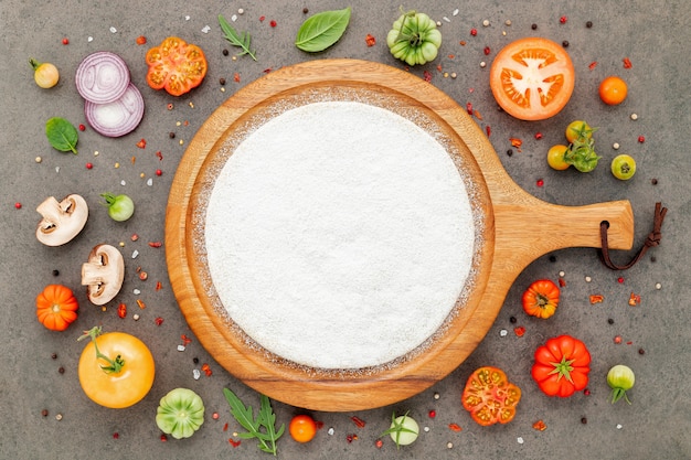 The ingredients for homemade pizza set up on dark stone background.