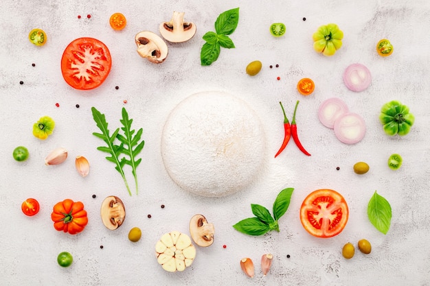 The ingredients for homemade pizza set up on white concrete background.