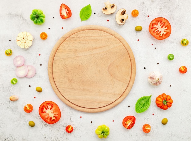 Gli ingredienti per la pizza fatta in casa allestiti su sfondo di cemento bianco.